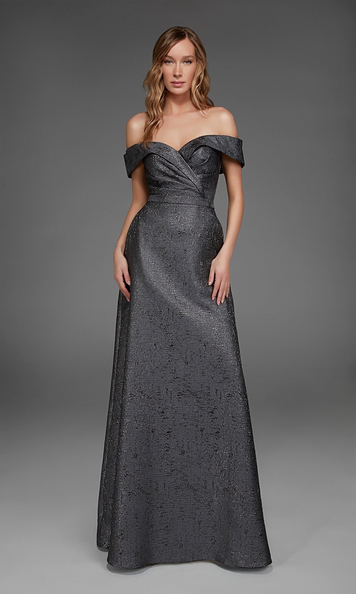 A woman wears the Alyce 27882 long formal dress in espresso, featuring an off-the-shoulder design, fitted bodice, and subtle jacquard texture, set against a plain gray background.